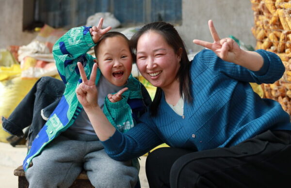 Little boy and mom smiling and giving the peace sign