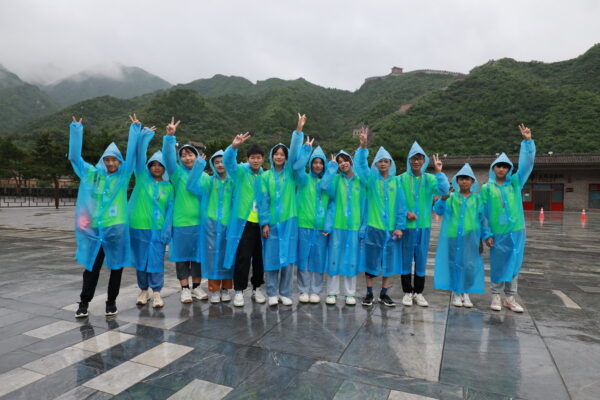 Group of teens in blue raincoats visit the Great Wall