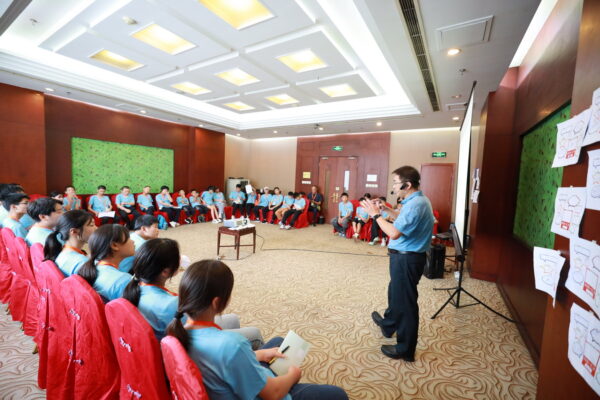 Group of teens in blue shirts listen to a lecture
