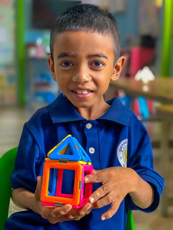 Little boy in blue school uniform plays with colorful toy