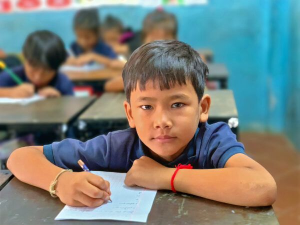 Boy in blue school uniform writing on a desk