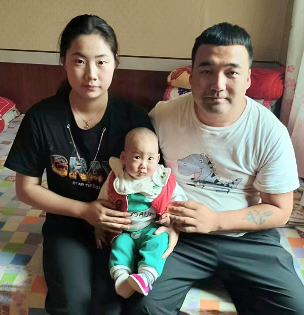 Two parents holding a small baby on their lap