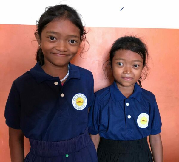 Two sisters in blue Love Without Boundaries school uniforms for 20 Years of Hope blog