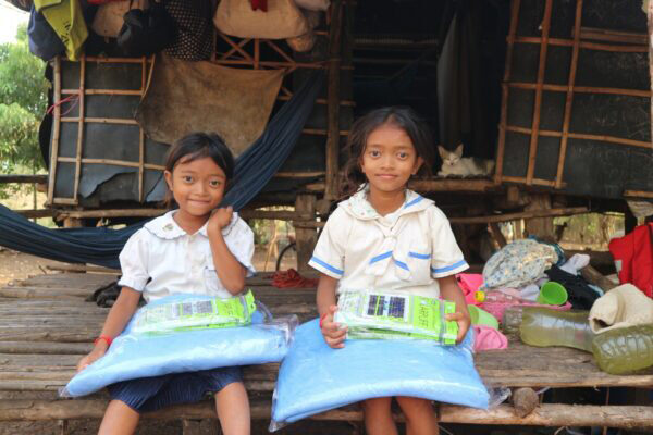 Two sisters sit at their home in Cambodia holding solarpuff solar lights