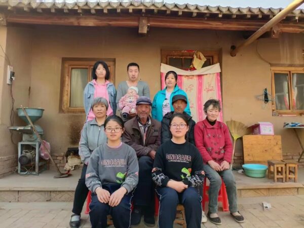 Chinese family with twin girls and a bay outside their rural home