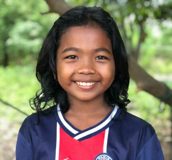 Cambodian girl smiling in a blue and red soccer shirt