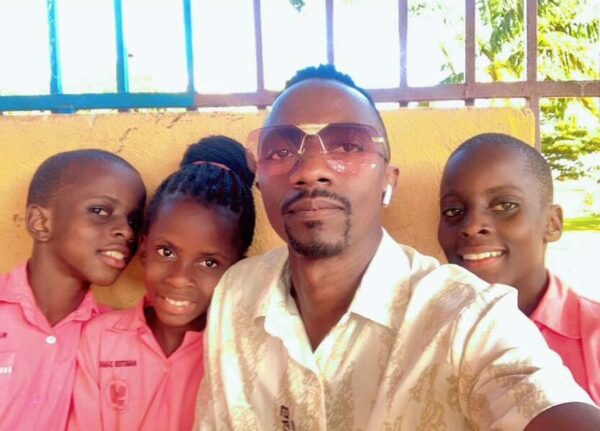 Twin boys and a girl wearing pink shirts with their uncle in Uganda