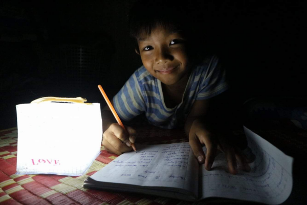 Boy in striped shirt doing homework with Solarpuff solar light