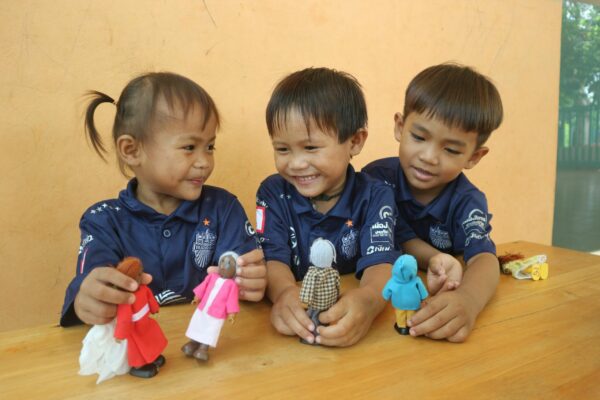 A little girl and 2 little boys play pretend at their early childhood development center