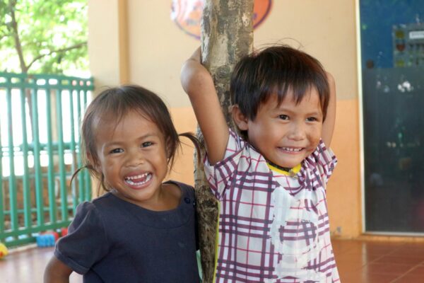 A sister and brother smiling at their school in Cambodia