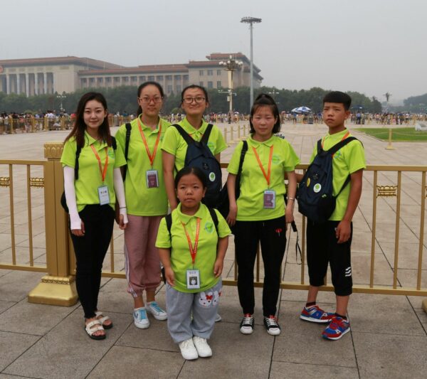 6 teens in fluorescent green shirts and orange lanyards in Tiananmen Square