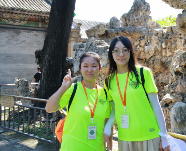 Two girls in matching fluorescent green shirts and orange lanyards visit the zoo