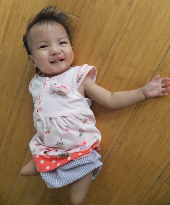 Smiling baby girl with one arm lying on floor