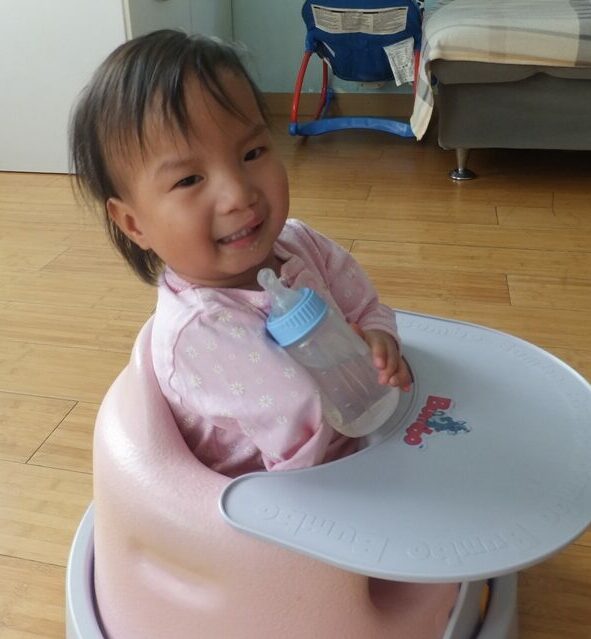 Baby girl smiling in a walker wearing pink