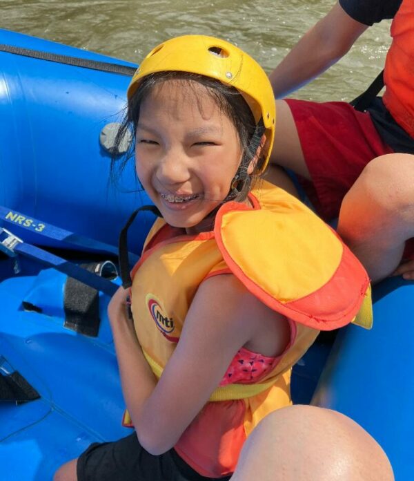 Young girl rafting wearing a bright yellow helmet and life jacket