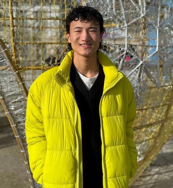 Teenage boy in a bright yellow jacket standing outside