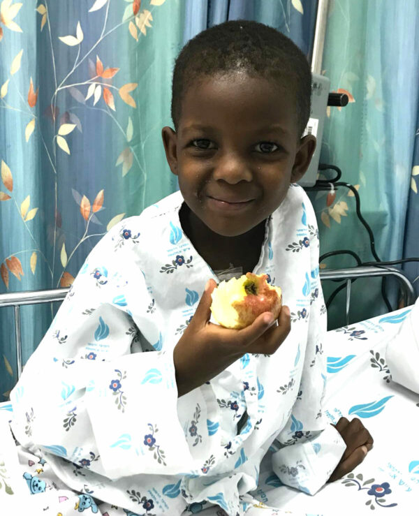 Young girl in hospital bed eating an apple