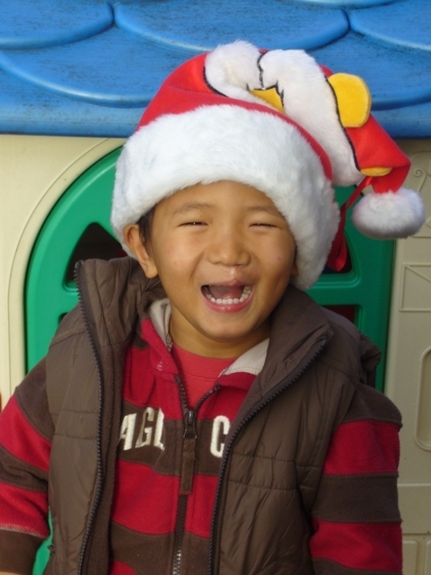 Little boy wearing a Santa hat and laughing