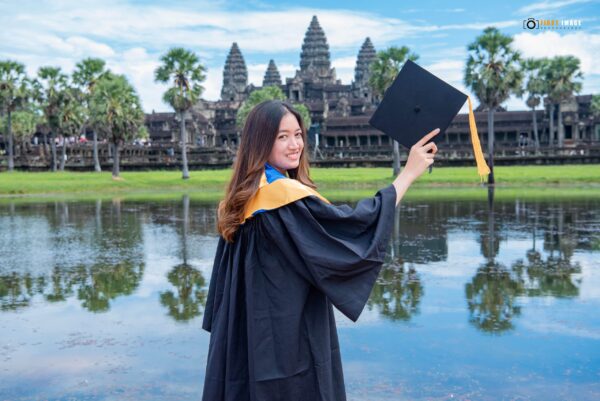 Young woman in cap and gown in front of Angkor Wat
