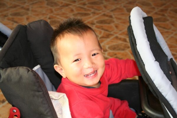 Baby boy in red sitting in a stroller