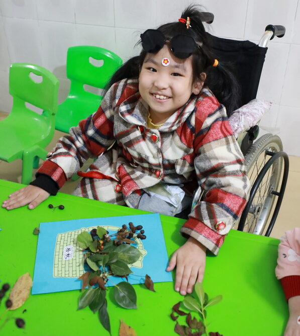 Young girl in a wheelchair making crafts at school