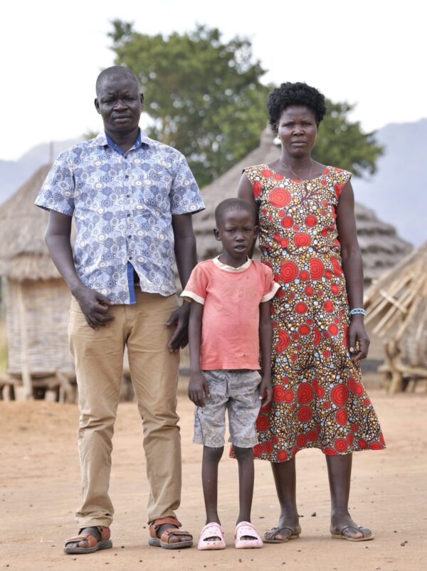 Ugandan parents and their son stand in their village