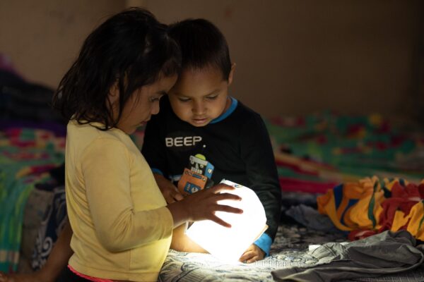 Two children examine a glowing solar light in Guatemala
