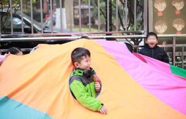 Two boys playing with a colorful parachute in school