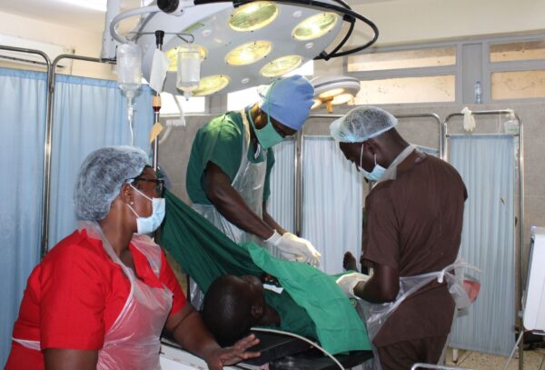 Ugandan operating room with three medical professionals performing surgery