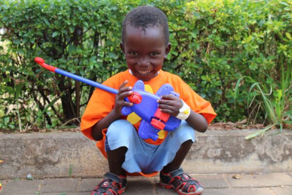 Ugandan boy in orange shirt with boy at LWB pediatric hernia mission