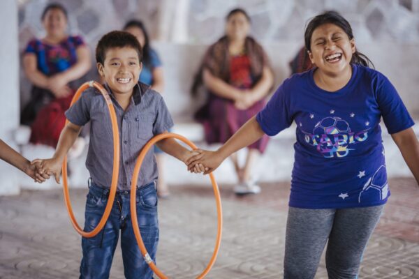 Boy and girl play with orange hula hoops