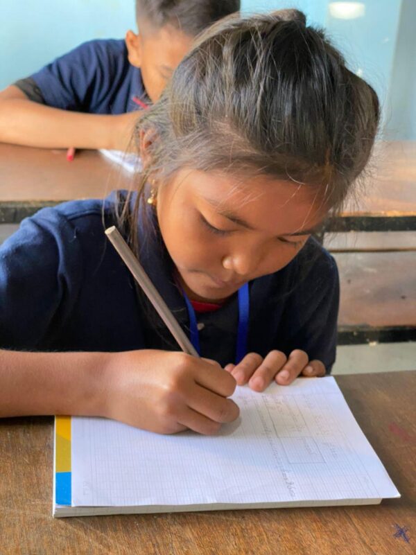 Girl in a blue school uniform writing in a notebook