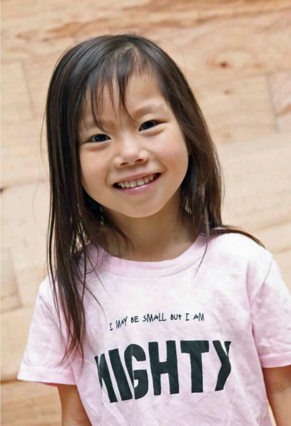 Little girl in a pink shirt that says, "I may be small but I am MIGHTY"
