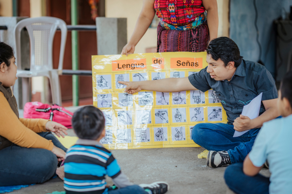 A man points to a sign language chart in Guatemala while teaching children