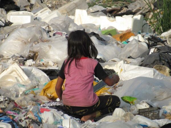 Little girl sitting in garbage at a landfill in Cambodia scavenging for recyclables
