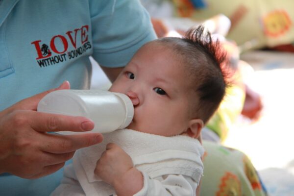 Baby with cleft lip drinking from a cleft bottle in a healing home