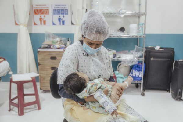 Woman in hospital holding baby after cleft repair surgery