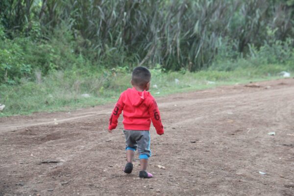 Boy in red alone on a dirt road