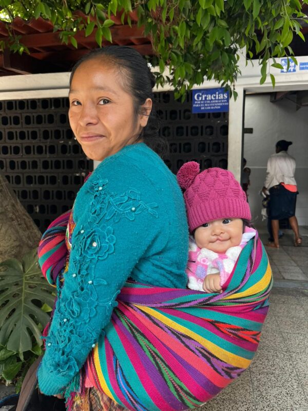 Guatemalan mom carrying baby in a colorful sling