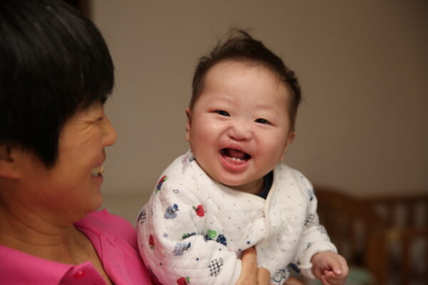 Laughing baby being held by nanny in pink