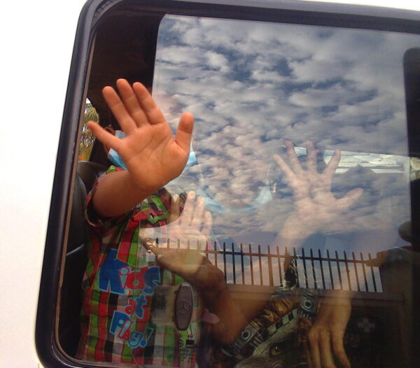Children's hands on the window of a police van