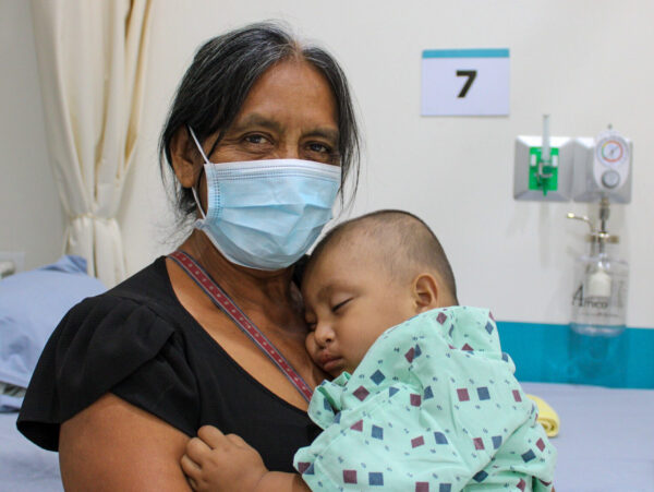 Woman holds boy following cleft repair surgery