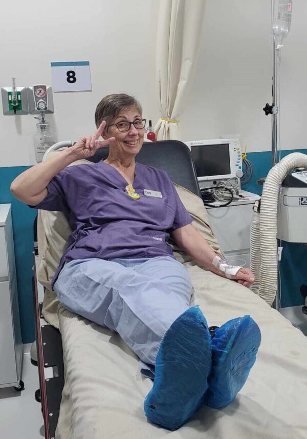 Woman in scrubs sitting in a hospital bed