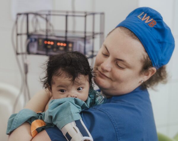 Nurse holding a baby after cleft surgery