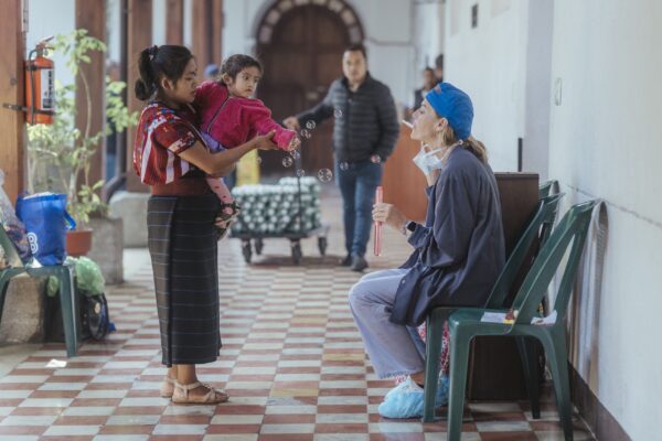 Mom holding a child talks to a volunteer at a hospital in Guatemala