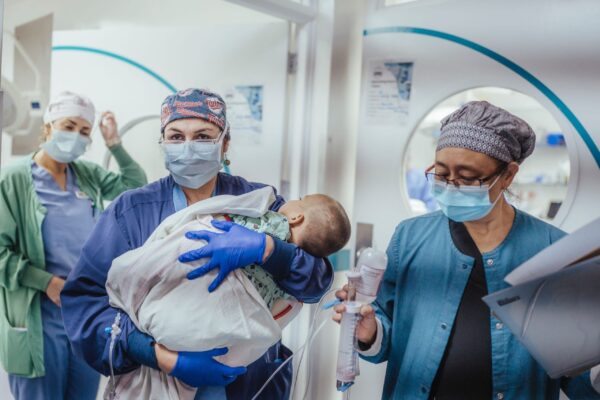 A baby heading out of the OR with 3 women