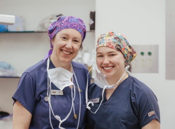 Two women in scrubs and surgical caps