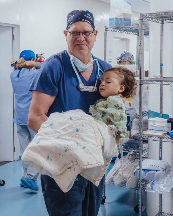 Doctor holds a toddler girl after cleft repair surgery