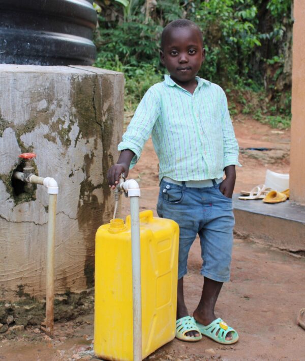 Boy fills a yellow jerry can with water in Uganda
