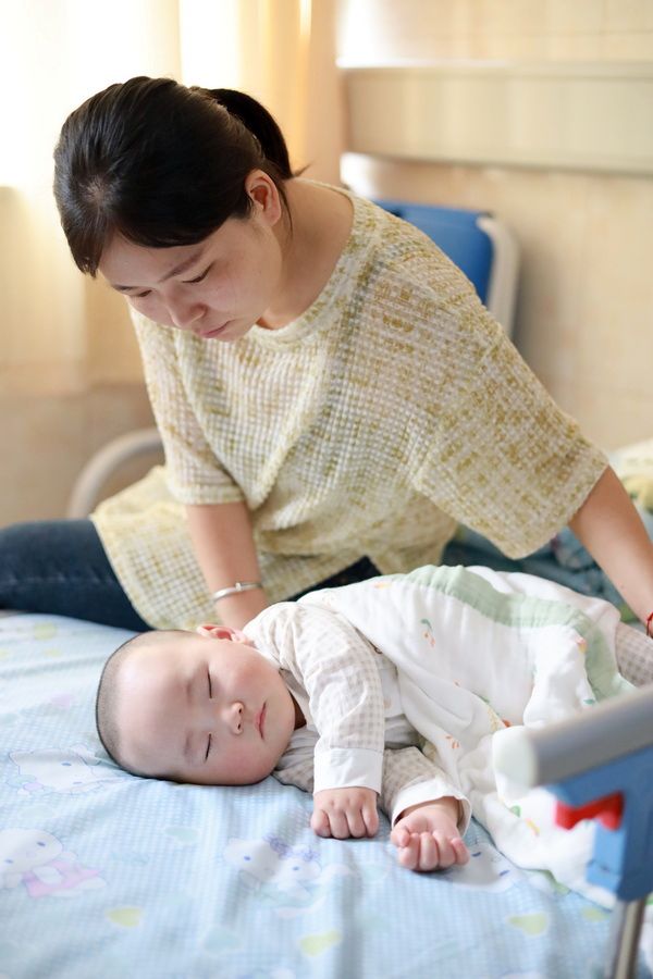 Mother watches baby lying in hospital bed after surgery with LWB's Unity Initiative